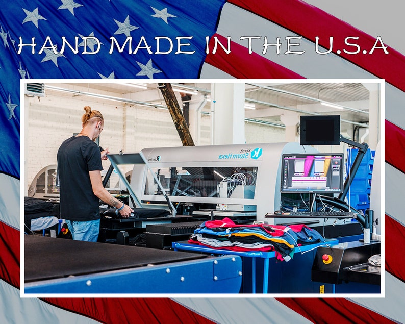 Peut inclure: Une personne utilisant une grande machine d'impression industrielle dans un environnement d'usine. La machine est utilis&eacute;e pour imprimer des motifs sur du tissu. Le texte "HAND MADE IN THE U.S.A." est affich&eacute; au-dessus de l'image.