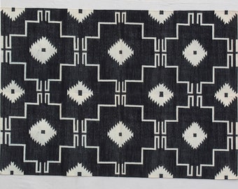 Könnte beinhalten: Schwarz-weißer geometrischer Teppich mit einem Rautenmuster. Der Teppich hat eine gewebte Textur.