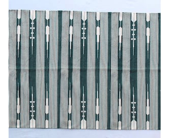Puede incluir: Una alfombra de rayas verdes y blancas con un patrón geométrico. La alfombra tiene un diseño tradicional con líneas blancas y formas geométricas sobre un fondo verde oscuro.