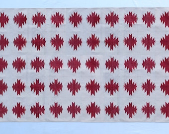 May include: A white rug with a repeating pattern of red geometric shapes. The rug has a simple, modern design.