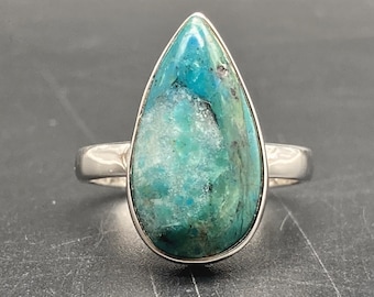 May include: A teardrop-shaped turquoise gemstone ring set in sterling silver. The stone has a blue-green colour with white inclusions.