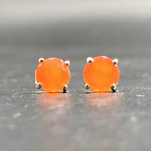 Könnte beinhalten: Ein Paar silberne Ohrstecker mit runden orangefarbenen Karneol-Edelsteinen.