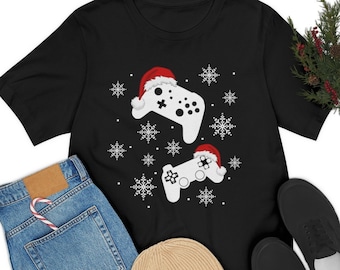 Könnte beinhalten: Schwarzes T-Shirt mit einem weißen und roten Weihnachtsdesign mit zwei Videospielcontrollern, die Weihnachtsmützen tragen und Schneeflocken.