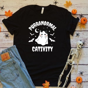 May include: Black t-shirt with a white graphic of a ghost cat with the text "Purranormal Cativity".