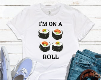 May include: White t-shirt with a graphic of four sushi rolls and the text "I'm on a roll".