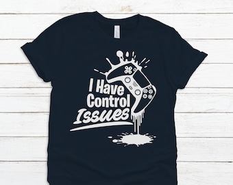 May include: A dark blue t-shirt with a white graphic of a video game controller dripping with paint. The text "I Have Control Issues" is printed on the shirt.