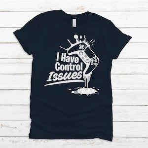 May include: A dark blue t-shirt with a white graphic of a video game controller dripping with paint. The text "I Have Control Issues" is printed on the shirt.