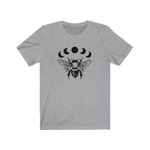 May include: A heather grey t-shirt with a black graphic of a bee with five crescent moons above it.