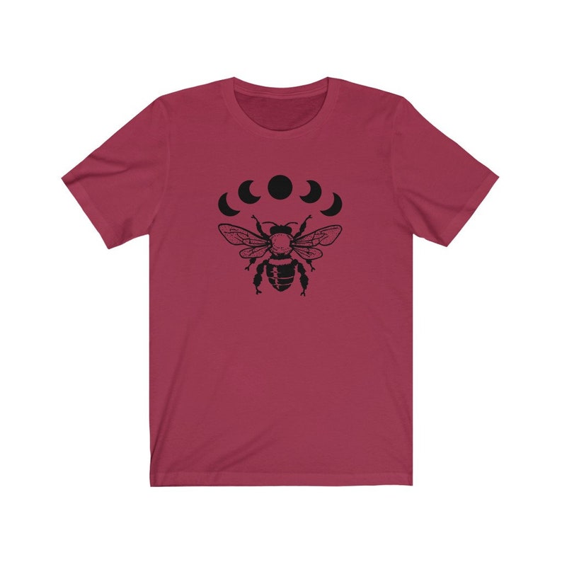 May include: A maroon t-shirt with a black bee and five black crescent moons printed on the front.