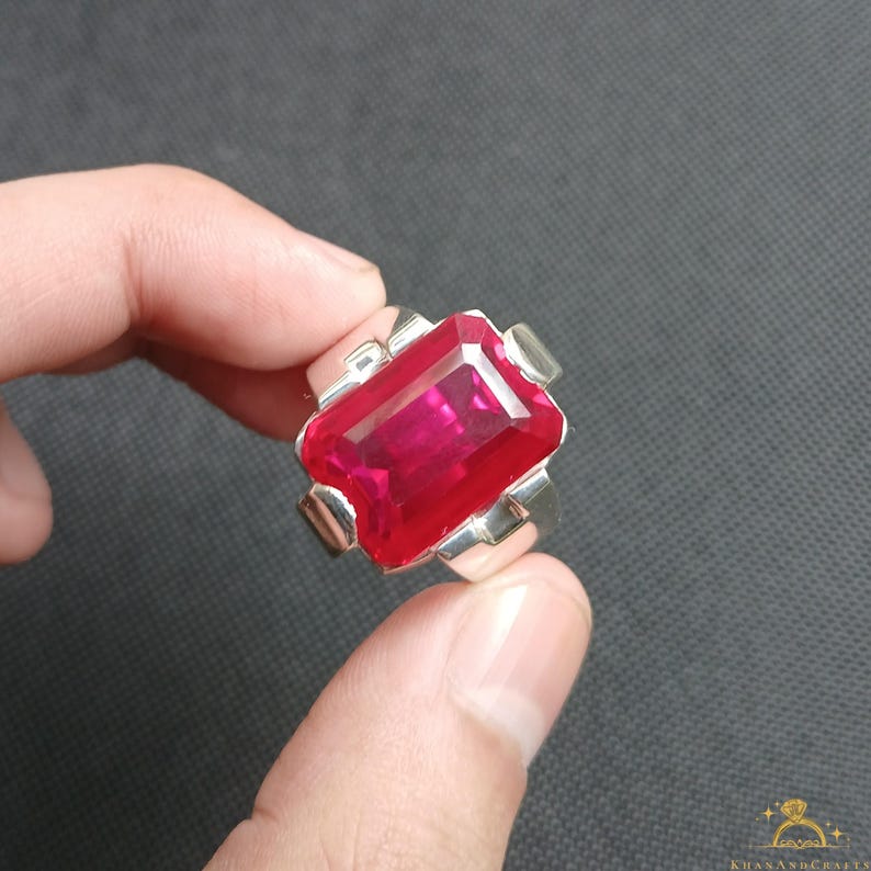 Puede incluir: Un anillo de plata con una gran gema roja rectangular. El anillo tiene un dise&ntilde;o simple y moderno con un acabado pulido. La gema es el punto focal, captando la luz y mostrando su color intenso.