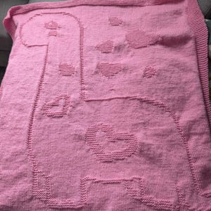 Può includere: Una copertina per neonati di lana rosa con un grande disegno a forma di cuore.