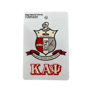 May include: A white sticker featuring the Kappa Alpha Psi Fraternity crest. The crest is red, black, and white, with Greek letters and the words "τελειωσις" and "δια φιλανθρωπίαν υονησιν πιστιν". Below the crest is the Greek letters "ΚΑΨ" in red.