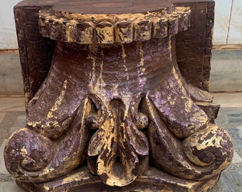 May include: A decorative wooden corbel with intricate carvings and a distressed, aged finish. The corbel is painted in shades of brown, gold, and purple, giving it a vintage look.