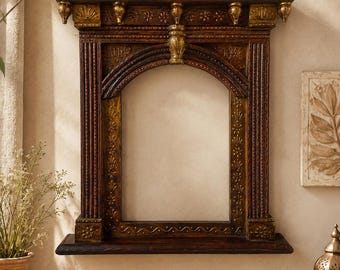 May include: A rectangular wall mirror frame featuring a dark brown wood finish with gold-toned accents. The frame has an arched top, fluted side columns, and decorative carved details along the edges, including floral motifs and finials.