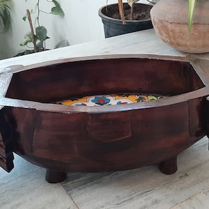 Puede incluir: Un cuenco de madera marrón oscuro con forma de elefante con un azulejo de patrón floral colorido en el interior.