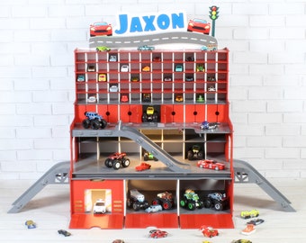 May include: Red wooden toy car garage with multiple levels and ramps. The garage has a sign that says "Jaxon" and is filled with toy cars.