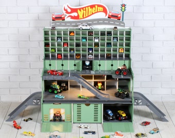 May include: A green wooden toy garage with a ramp and multiple levels for storing toy cars. The garage has a sign that says "Wilhelm" and a red, white, and blue color scheme. There are many toy cars parked inside and outside the garage.