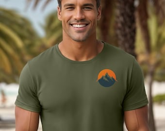 May include: A man wearing a green t-shirt with a small mountain and sun graphic on the left chest.
