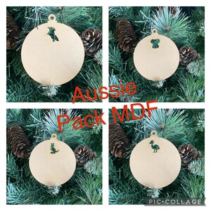 May include: Four wooden Christmas ornaments with Australian animal cutouts. The ornaments are round and have a hole at the top for hanging. The animals are a kookaburra, a koala, a kangaroo, and an emu. The ornaments are labeled "Aussie Pack MDF".