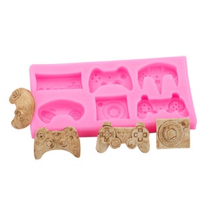 May include: Pink silicone mould with eight different video game controller designs. The mould is empty and ready to be used to make chocolate or candy.