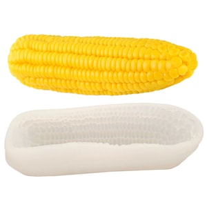 Può includere: Uno stampo in silicone bianco a forma di pannocchia di mais. Lo stampo ha una texture dettagliata per creare chicchi di mais realistici. Una pannocchia di mais gialla è mostrata sopra lo stampo.