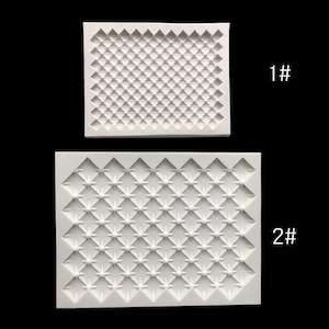 Pode incluir: Dois moldes de silicone branco para assar. O molde superior tem um padrão de grade quadrada. O molde inferior tem um padrão de grade quadrada com um pequeno círculo no centro de cada quadrado.