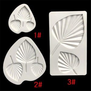 May include: Three white silicone molds for baking, shaped like palm leaves. The molds are numbered 1, 2, and 3.