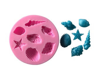 May include: Pink silicone mold with eight different seashell and starfish shapes.  The mold is filled with teal colored resin casts of the shapes.