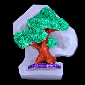 May include: A white silicone mold shaped like a tree with a brown trunk and green leaves. The mold is designed for making decorative items.