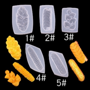 May include: Five silicone moulds for making miniature bread shapes. The moulds are numbered 1 through 5. The moulds are shown with examples of the finished bread shapes.