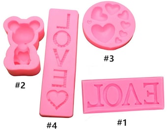 May include: Four pink silicone molds for baking. The molds are shaped like a bear, a heart with the word "LOVE" inside, a heart with the word "LOVE" inside, and a heart with the word "LOVE" inside. The molds are numbered 1 through 4.