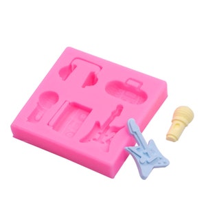 Pode incluir: Forma de silicone rosa com seis cavidades em forma de microfone, fones de ouvido, guitarra, toca-fitas e mala. Há também uma pequena guitarra azul e branca feita de silicone.