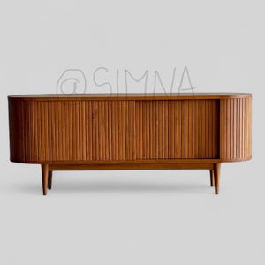 以下が含まれることがあります： 2 つの引き戸が付いた、ミッドセンチュリーモダンな木製キャビネット。キャビネットは丸みを帯びた楕円形で、濃い茶色の木で作られています。ドアは縦の羽根板でできています。