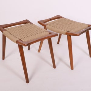 Puede incluir: Dos taburetes de madera con asientos de cuerda trenzada. Los taburetes tienen un diseño sencillo y moderno de mediados de siglo.