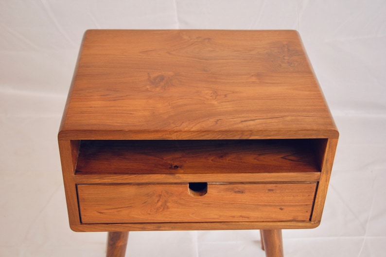 May include: A wooden bedside table with a drawer and a shelf. The table has a light brown finish and a simple design.