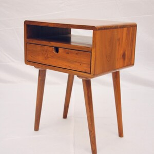 May include: A wooden end table with a single drawer and a shelf. The table has four tapered legs and a light brown finish.