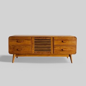 Puede incluir: Un mueble de TV de madera de estilo moderno de mediados de siglo con cuatro cajones y una puerta de listones. El mueble es de madera marrón claro y tiene un frente curvo.