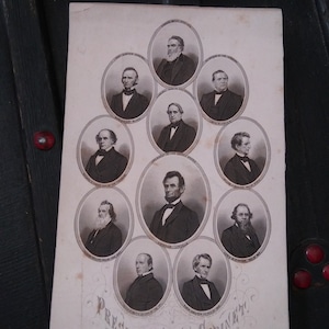 May include: A black and white photo of President Abraham Lincoln and his cabinet. The photo is in an oval frame and the text "President and Cabinet" is printed below the photo.