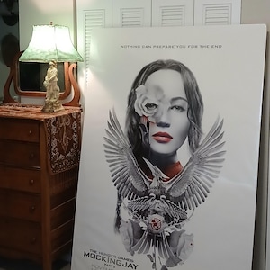 May include: A poster for "The Hunger Games: Mockingjay - Part 2" featuring a woman's portrait with a rose and a phoenix design. The poster includes the text "Nothing Can Prepare You For The End" and the release date, November 20.