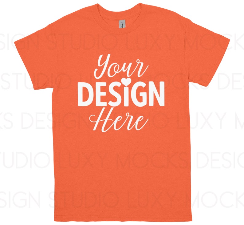 May include: Orange t-shirt with the text "Your DESIGN Here" in white script and block letters. A small white heart is between the words "DESIGN" and "Here". The t-shirt is a crew neck style.