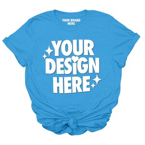 May include: A light blue t-shirt with the text "YOUR BRAND HERE" and "YOUR DESIGN HERE" in white. The shirt has a knotted front.