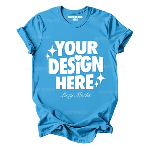 May include: A light blue t-shirt with the text "YOUR DESIGN HERE" in white. The text is surrounded by small white stars and hearts. The text "Luxy Mocks" is also printed in white below the main text.