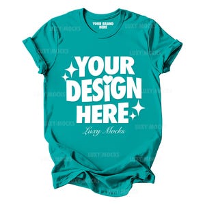 Puede incluir: Una camiseta turquesa con el texto "YOUR BRAND HERE" y "YOUR DESIGN HERE" en blanco. El texto "Luxy Mocks" también está en blanco.