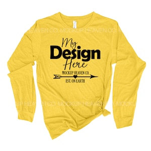 May include: Yellow long-sleeve t-shirt with a black graphic that says "My Design Here" with an arrow and the text "MOCKUP HEAVEN CO. EST. ON EARTH".
