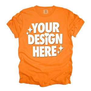 Puede incluir: Camiseta naranja con el texto "YOUR DESIGN HERE" en blanco. El texto está estilizado con estrellas y corazones.