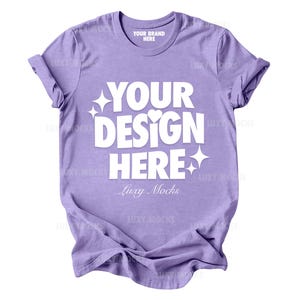 May include: A purple t-shirt with the text "YOUR DESIGN HERE" in white. The text is in a bold, playful font with a heart and stars. The text "Luxy Mocks" is below the main text in a smaller font.