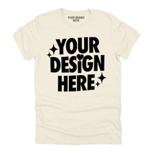 Puede incluir: Una camiseta de color crema con texto negro que dice "YOUR BRAND HERE" y "YOUR DESIGN HERE" con un pequeño corazón y estrellas.