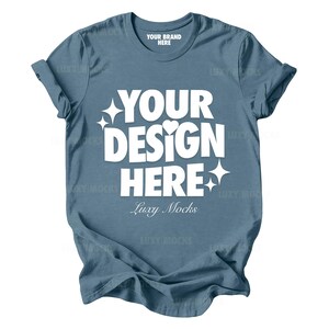 Peut inclure: Un t-shirt bleu avec le texte "YOUR BRAND HERE" sur l'étiquette du col et "YOUR DESIGN HERE" en texte blanc sur le devant. Le texte "Luxy Mocks" est également imprimé sur le devant du t-shirt.