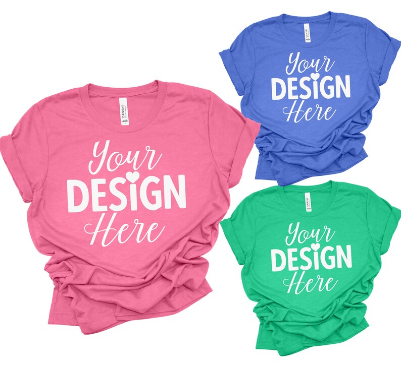 May include: Three t-shirts in different colors: pink, blue, and green. Each shirt has the text "Your Design Here" printed on the front in white with a small heart symbol.