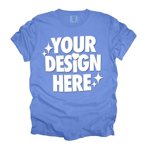 May include: A light blue t-shirt with the text "YOUR DESIGN HERE" in white. The text is styled with sparkles and a heart.